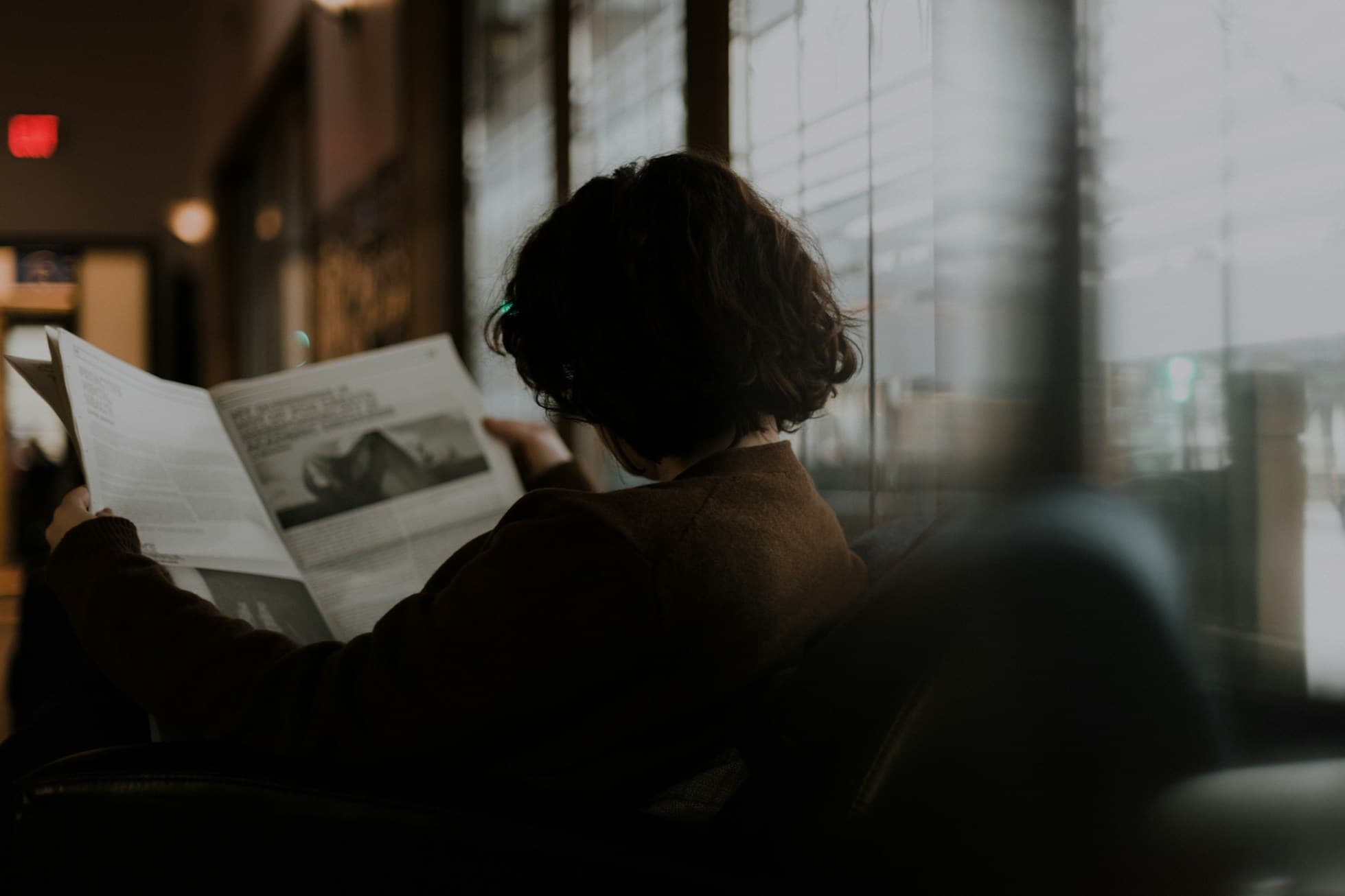 Person reading a newspaper in a warmly lit room